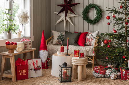stue dekorert i juletema med julestjerne, krans, juletre, nisse, julegaver, stearinlys
