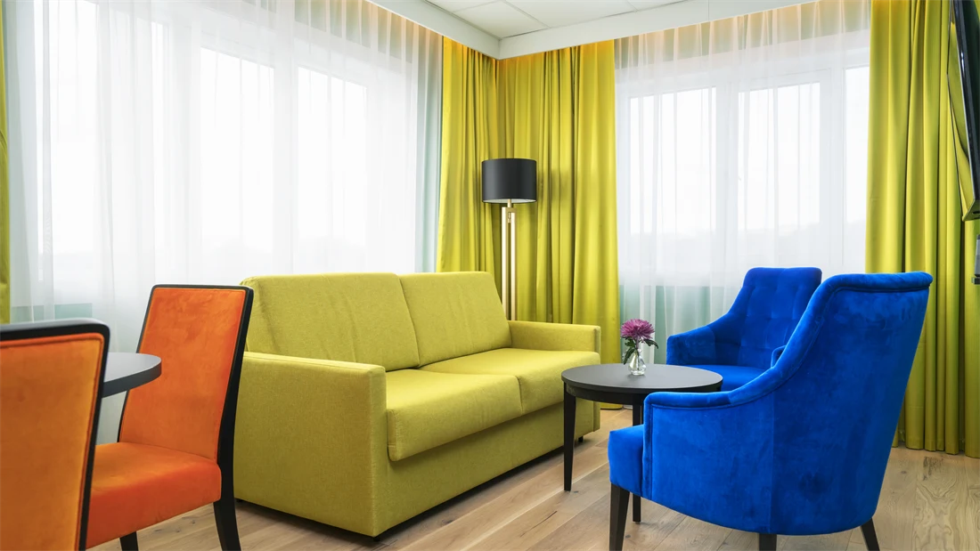 Gul sofa med lenestoler i forskjellige farger på suite Thon Hotel Europa i Oslo sentrum rett ved Slottsparken