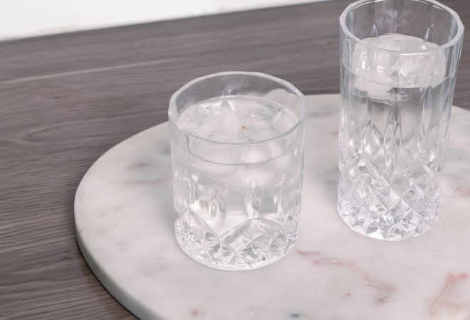 To glass med vann, et kort og et høyere, som står på en marmorplate