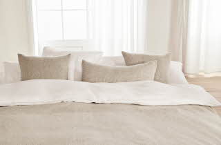 En seng med beige sengetøy