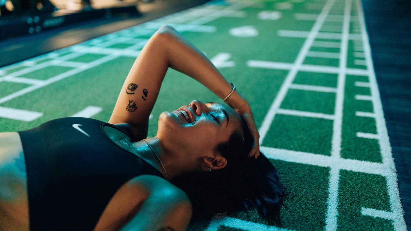 smilende svett dame som ligger på gulvet i et treningssenter i sort sportsbh