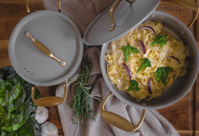 En gryte med kokt pasta, brokkoli og rødløk.