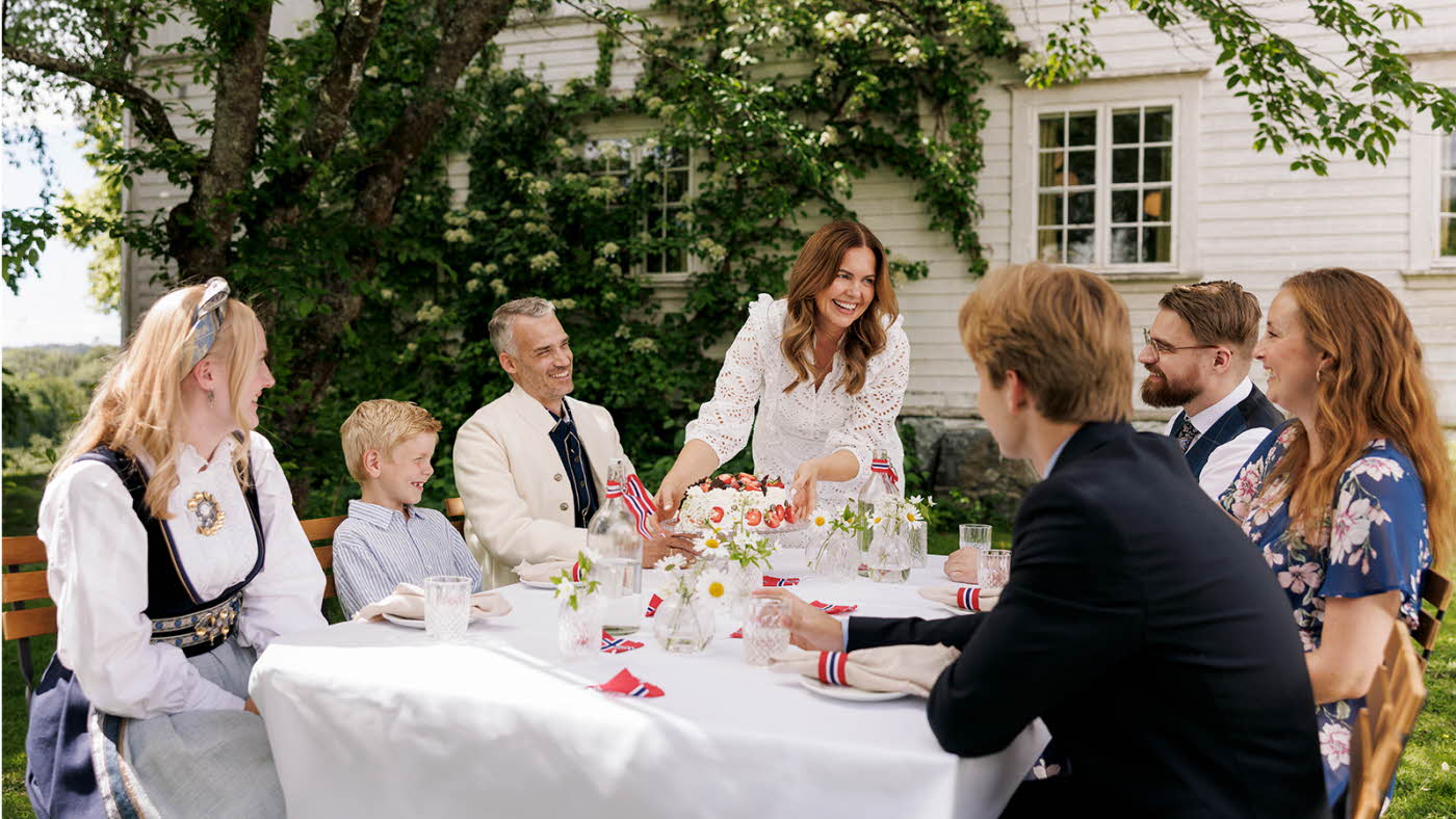 Familie som er samlet i hagen rundt bordet for å feire 17. mai