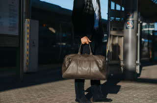 En mann som bærer på en brun bag