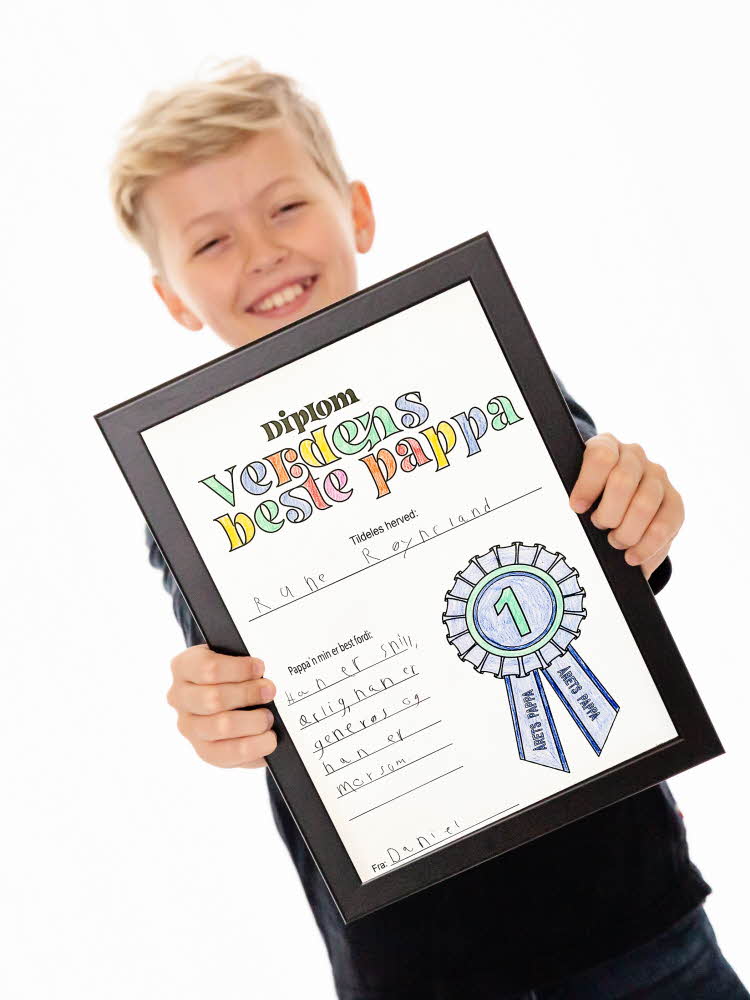 Gutt holder et diplom han har laget seg til far