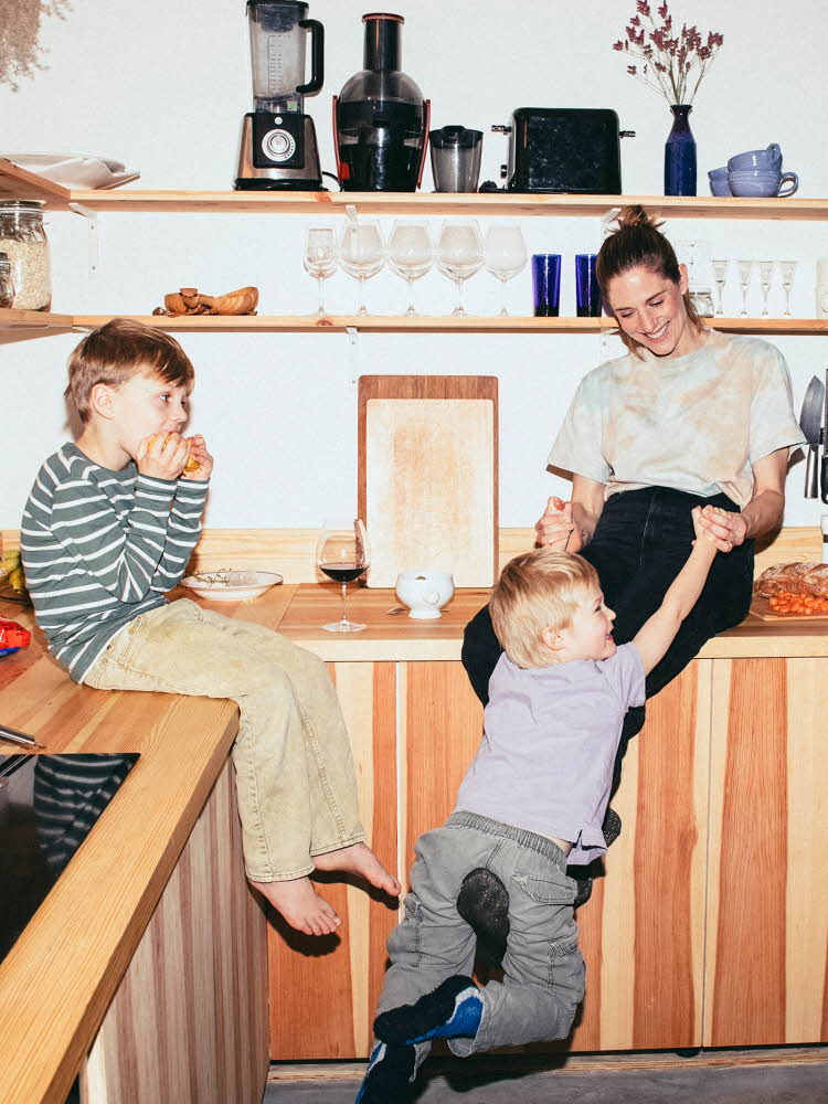 Familie med mor og to små gutter leker på kjøkken