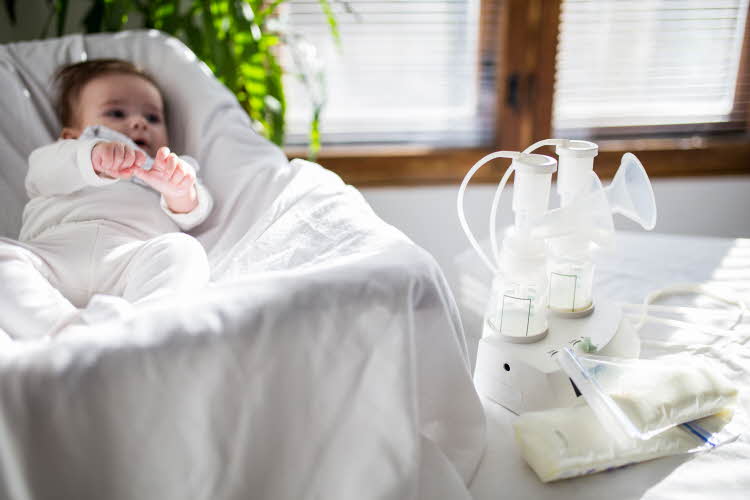 barn som ligger i krybbe med ammepumpe