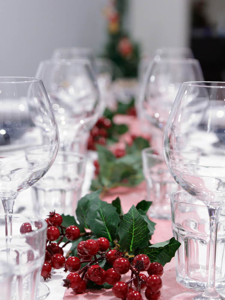 Nærbilde av langbord som er pyntet med glass, rød løper og røde bær. Foto til artikkel om bryllupsmenyer tilpasset sesong.