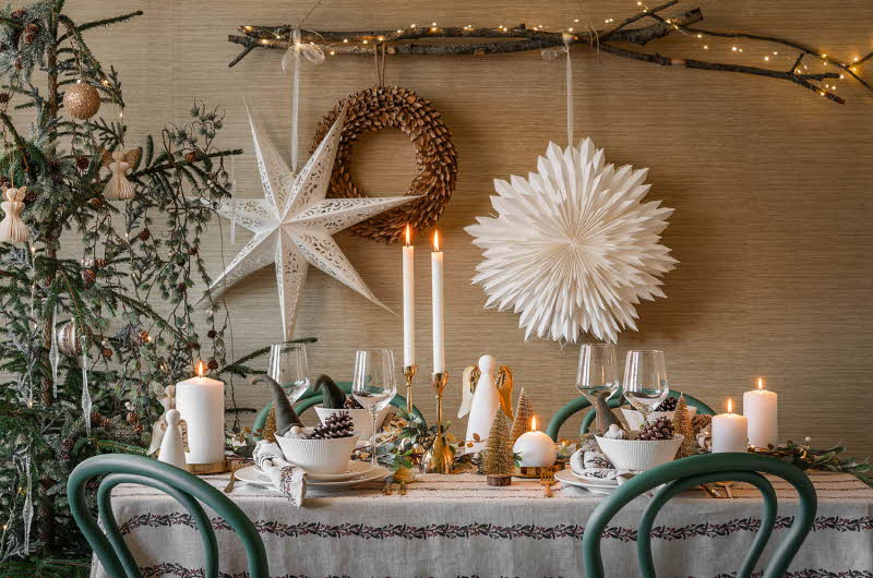 Spisebord dekorert med julepynt, papirstjerner, lys, figurer og juletre