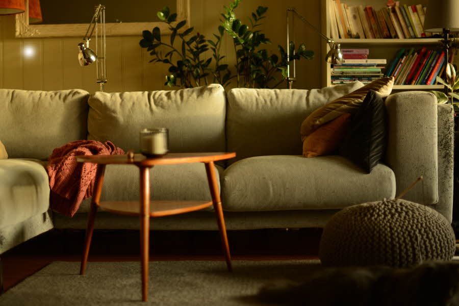 Stue med lun atmosfære og sofa med puter i høstlige farger og trebord med stearinlys i front