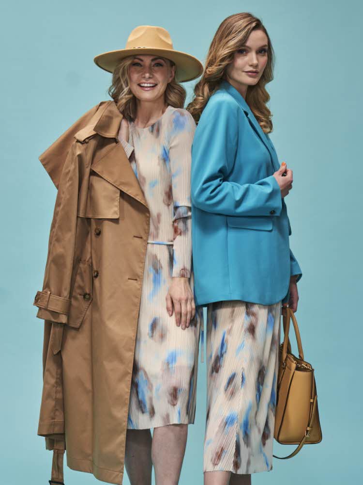 Blå bakgrunn med to damer, en med mønstret kjole og brun kåpe og en med mønstret skjørt og turkis dressjakke