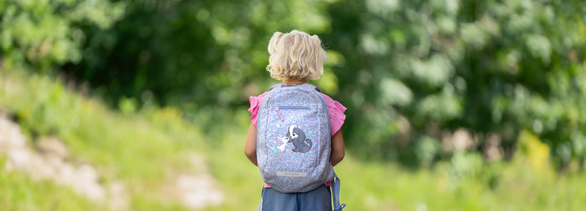 Bilde av jente med skolesekk bakfra, i grønt landskap