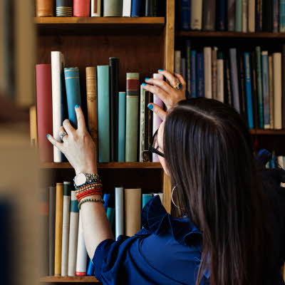 Dame leter etter bok i bokhylle