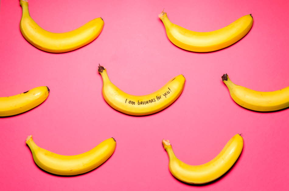 7 gule bananer som ligger på en rosa plate. På den ene bananen står det skrevet med sort tusj" I`m bananas for you"