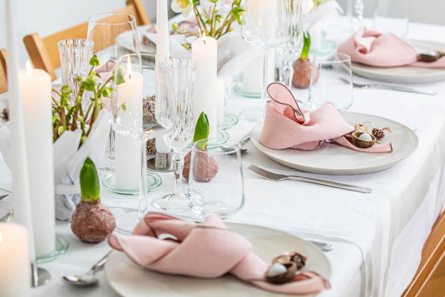 Langbord dekker til gjester med rosa servietter og grønn naturlig dekorasjon