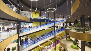 Innsiden av kjøpesenteret Lagunen. Åpent midtpunkt i bygget, med etasjer rundt og rulletrapper i sterke farger i sentrum. Foto til artikkel om Norges største kjøpesenter.