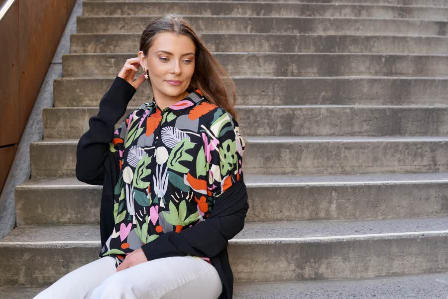 Dame med 70-talls inspirert jakke som sitter i en trapp
