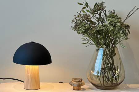 En Mushroom bordlampe står ved siden av en vase med blomster