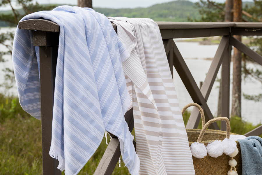 Et blå og et beige badehåndkle henger over gjerdet på på en veranda