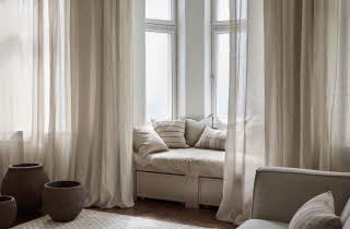 Et vindussete med pynteputer med gardiner hengende rundt