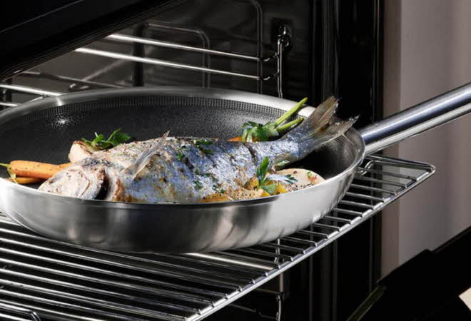 En stekepanne med en hel fisk i som står i stekeovnen.