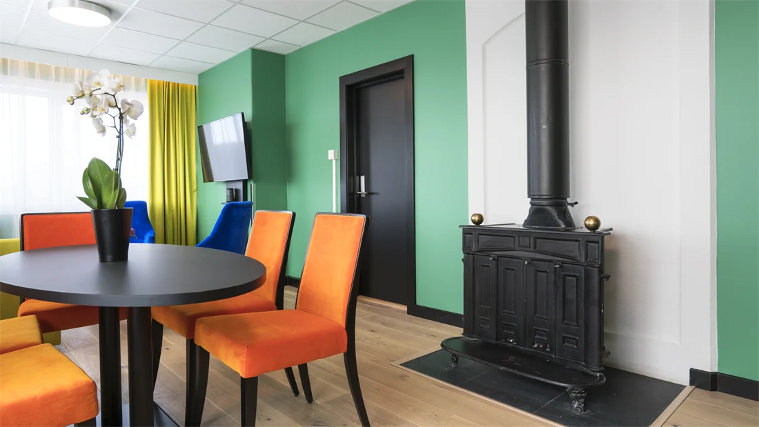 Peis, TV, bord, orange stoler på suite på Thon Hotel Europa i Oslo sentrum rett ved Slottsparken