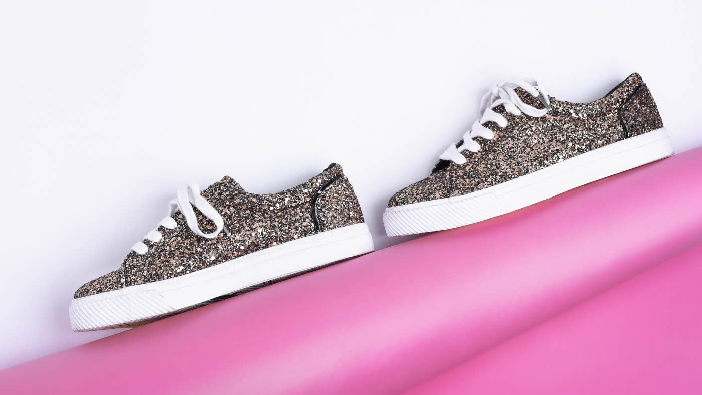 Glitrende sneakers mot en hvit og rosa bakgrunn