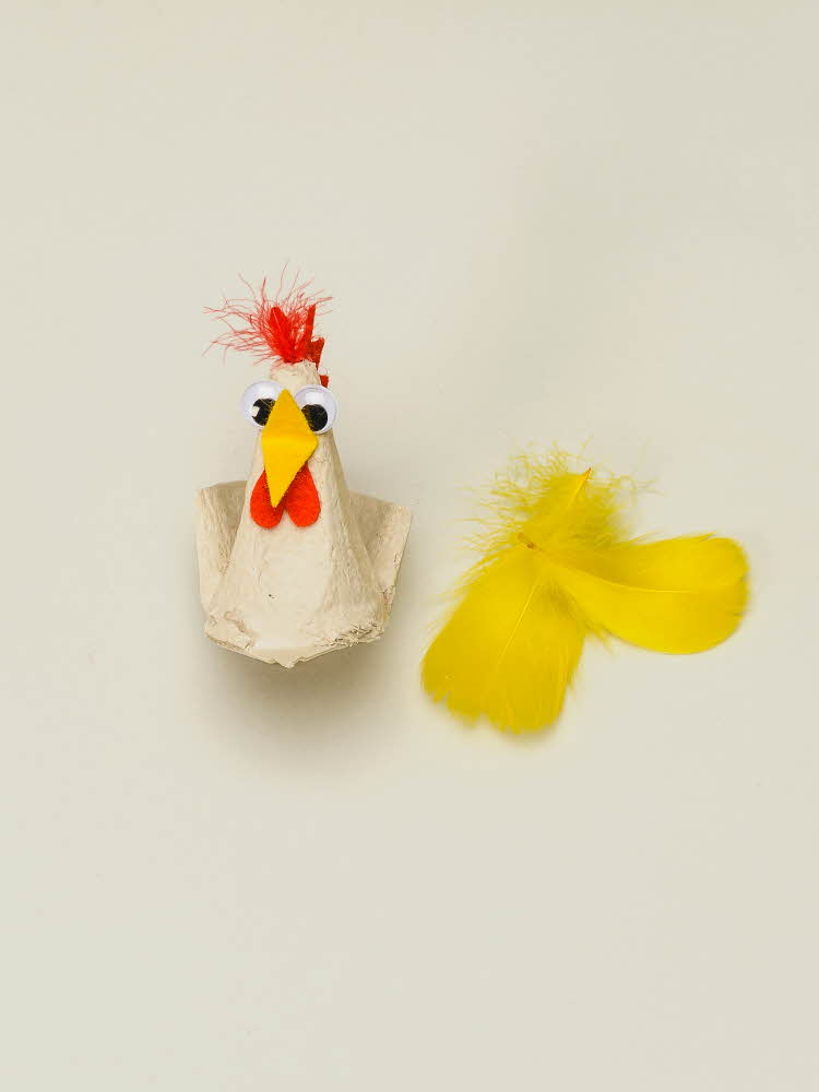 En eggekartong omgjort til en høne som mangler vinger Høne laget av eggekartong, filtbiter og fjær