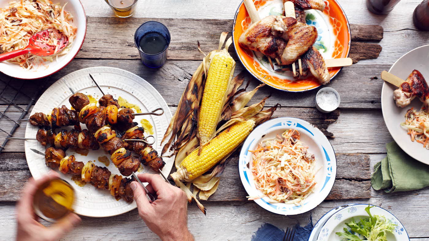 Bord dekket med grillspyd, maiskolber og diverse grillmat