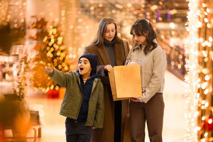 Gutt peker begeistert på noe han ser og damer som ser i shoppingpose