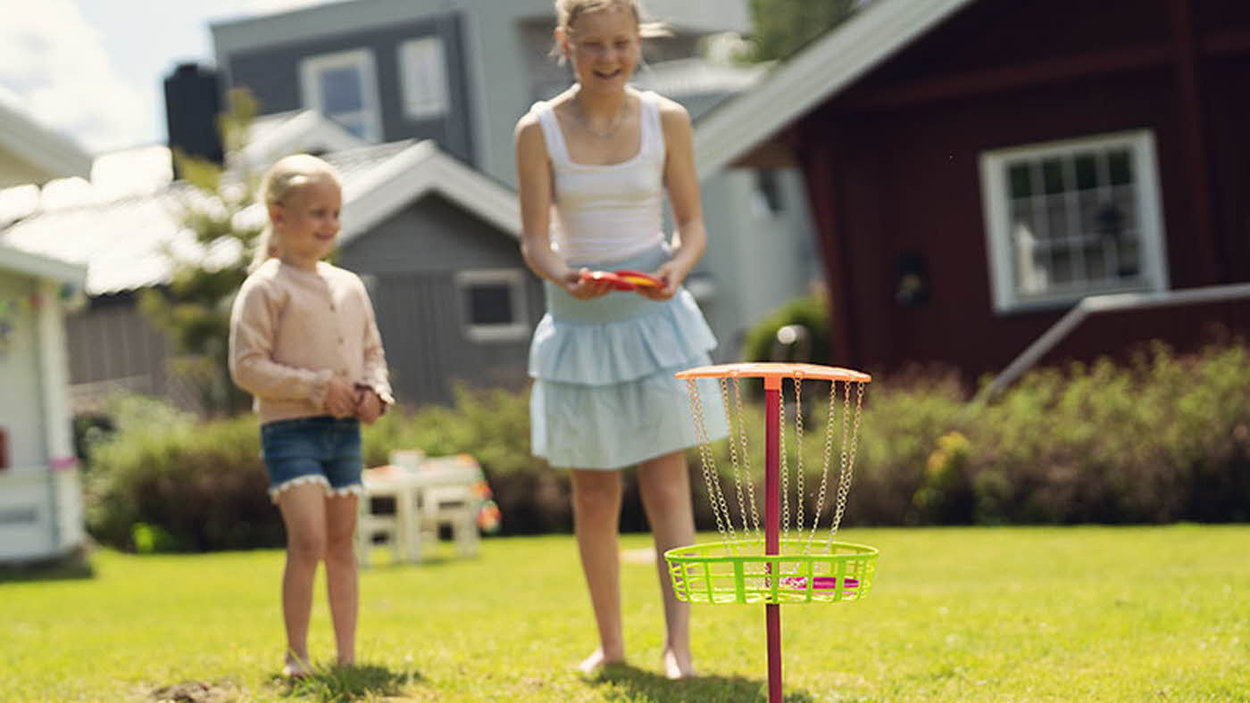 Jenter som leker i hagen med frisbeegolf
