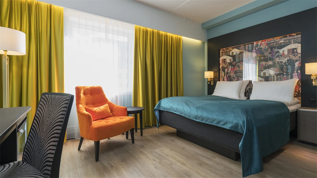 Dobbeltseng, orange lenestol og skrivebord i dobeltrom på Thon Hotel Linne