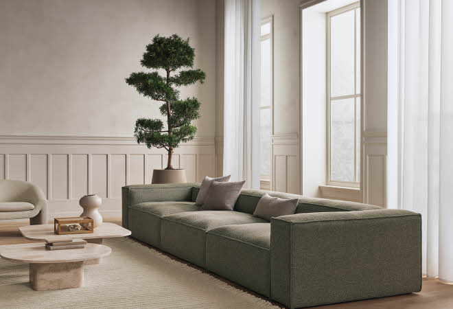 Et moderne og lyst stueinteriør med grønn sofa, grå puter og to kaffebord.