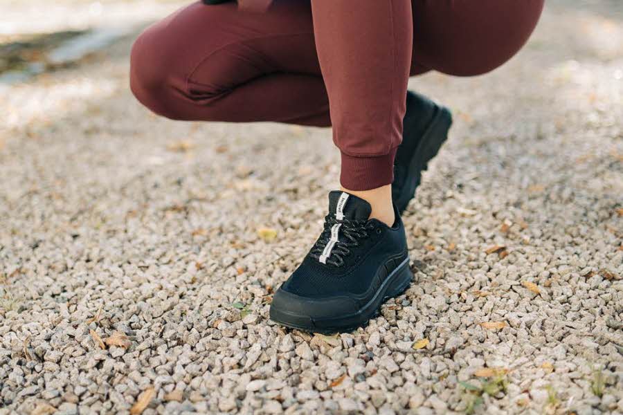 En kvinne som sitter på huk iført sorte gaitline-sko
