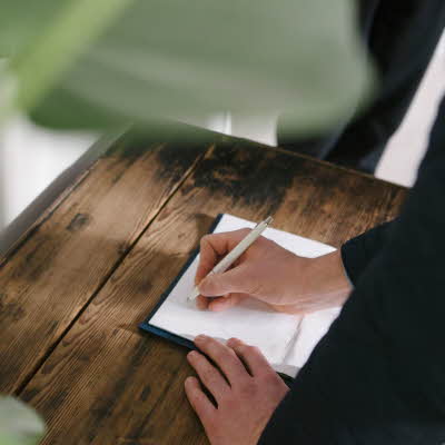 Hånd som signerer ark som ligger på trebord
