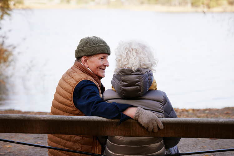 Eldre mann med lue sitter sammen med dame på en benk