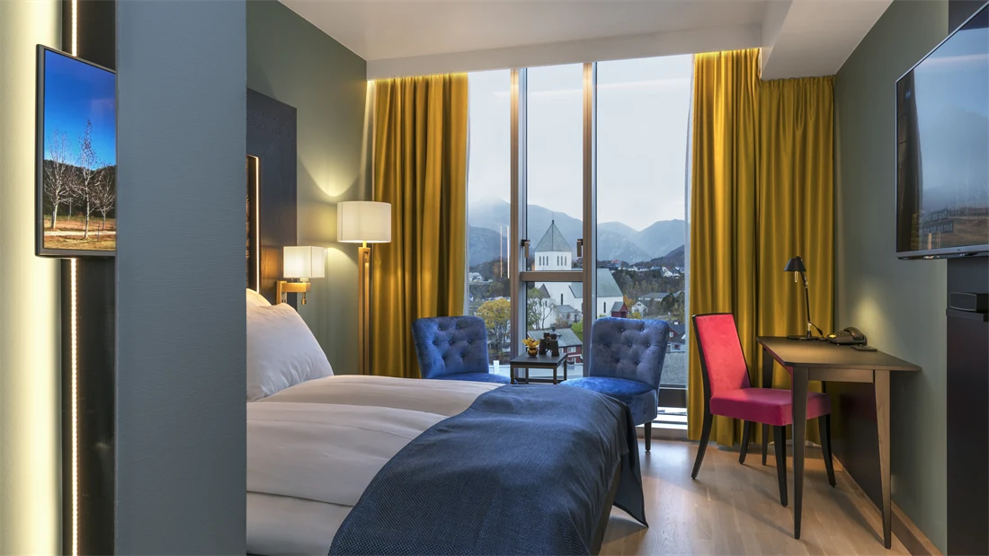 Dobbeltseng og to stoler med utsikt fra rommet på standard double room på Thon Hotel Lofoten i Svolvær