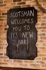 Skilt der det står "Scotsman welcomes you to its new bar"