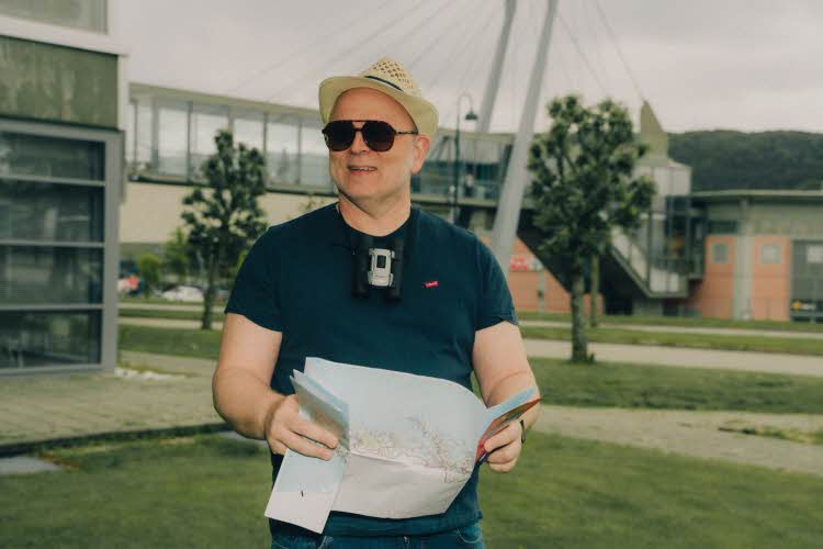 mann utenfor moa med hatt, solbrriller og kart