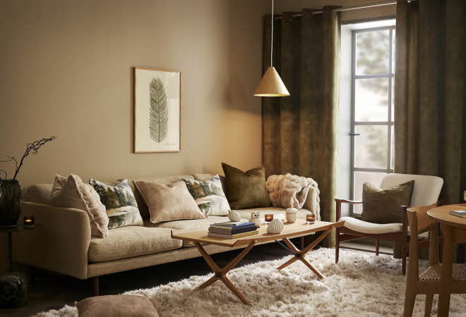 En stue med en beige sofa, en lenestol og et stuebord