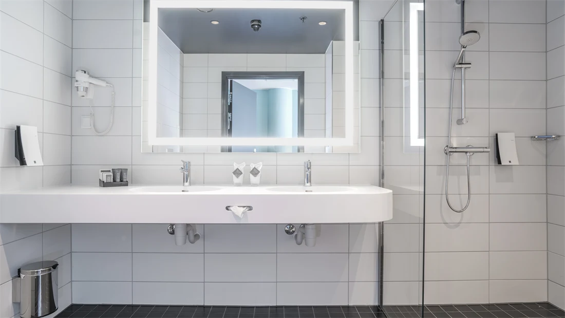Romslig bad med to vasker, speil med led lys rundt og dusj i handicap superior room