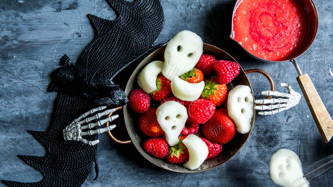 Fat med fruktfigurer som hodeskaller med halloweendekorasjon rundt