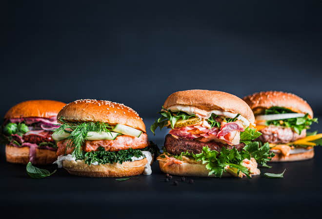 Fire gourmetburgere med ulike ingredienser og typer brød.