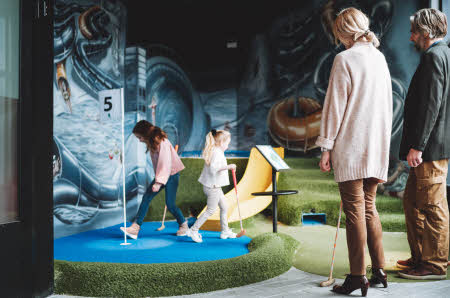 Besteforeldre som spiller minigolf med barnebarna