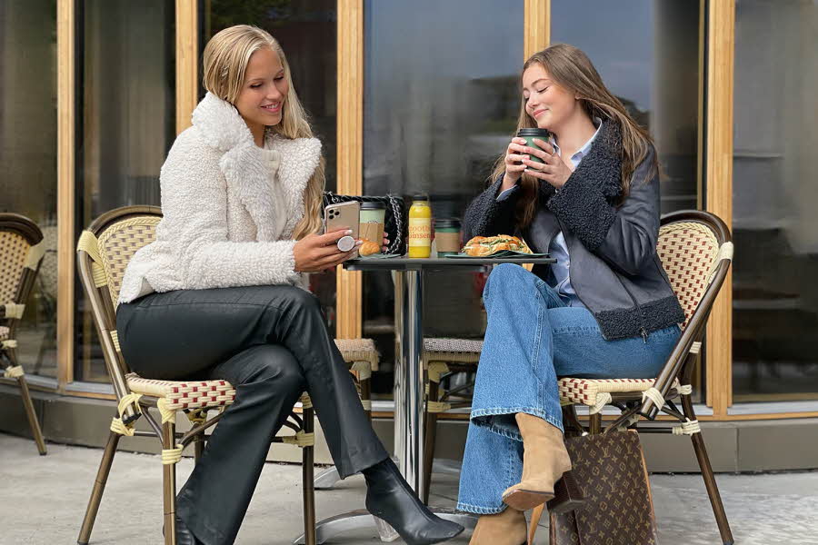 To damer sitter på ute kafé