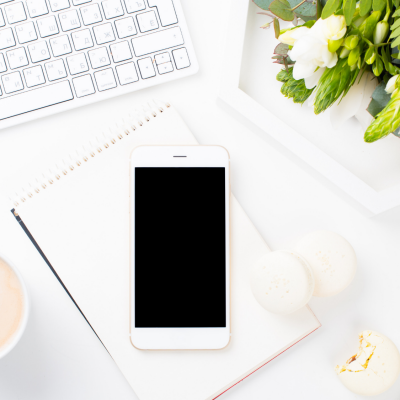 Telefon, tastatur og kaffekopp på et skrivebord