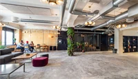 Interiør fra kontoret til The Oslo Company, stor og åpen sosial sone med rustikke detaljer som betonggulv og ventilasjon, grønne planter og lyse farger på veggene
