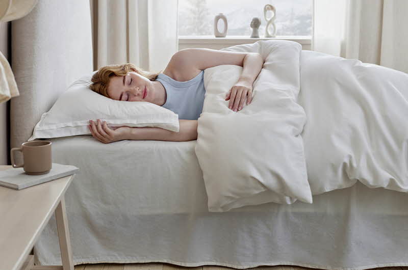 dame som sover på hvit dunpute og dundyne