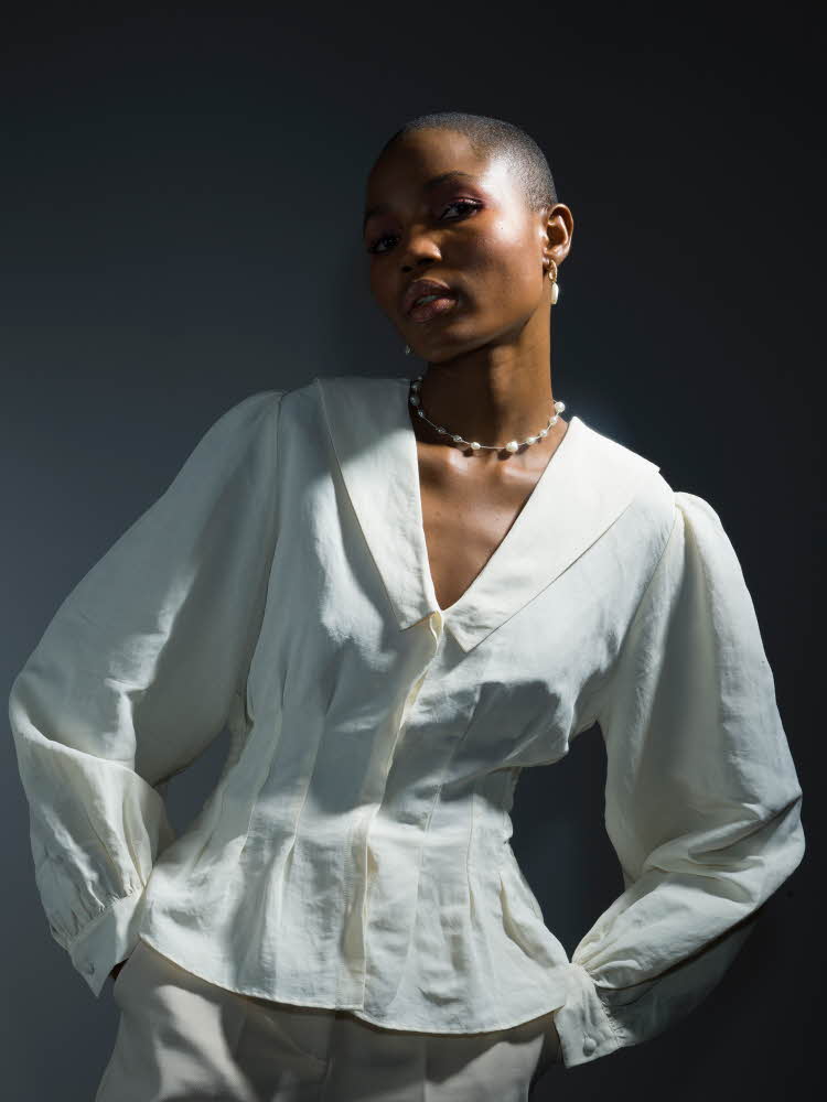 Dame med hvit bluse med innsvinget midje poserer for kamera