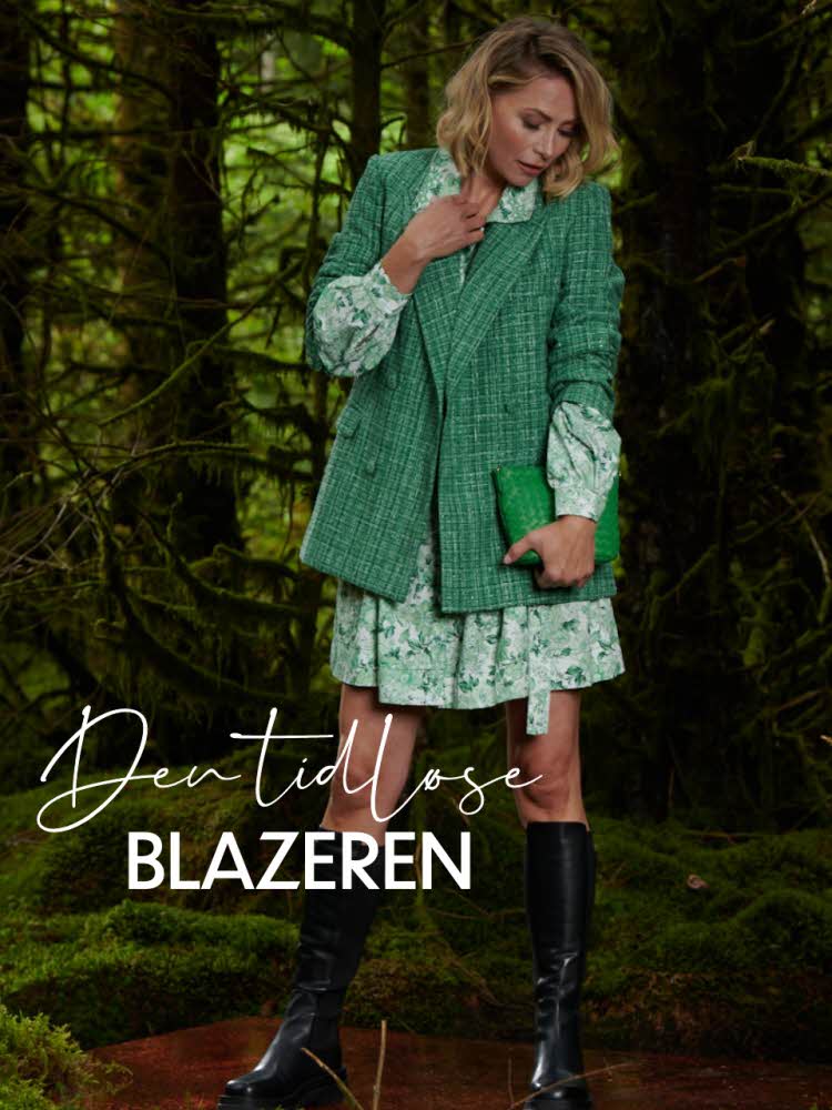 Den tidløse blazeren. Dame med grønn blazer står i skogen.